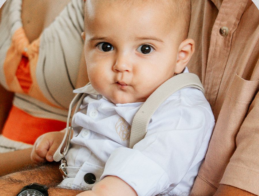Bebê no colo dos pais no batizado